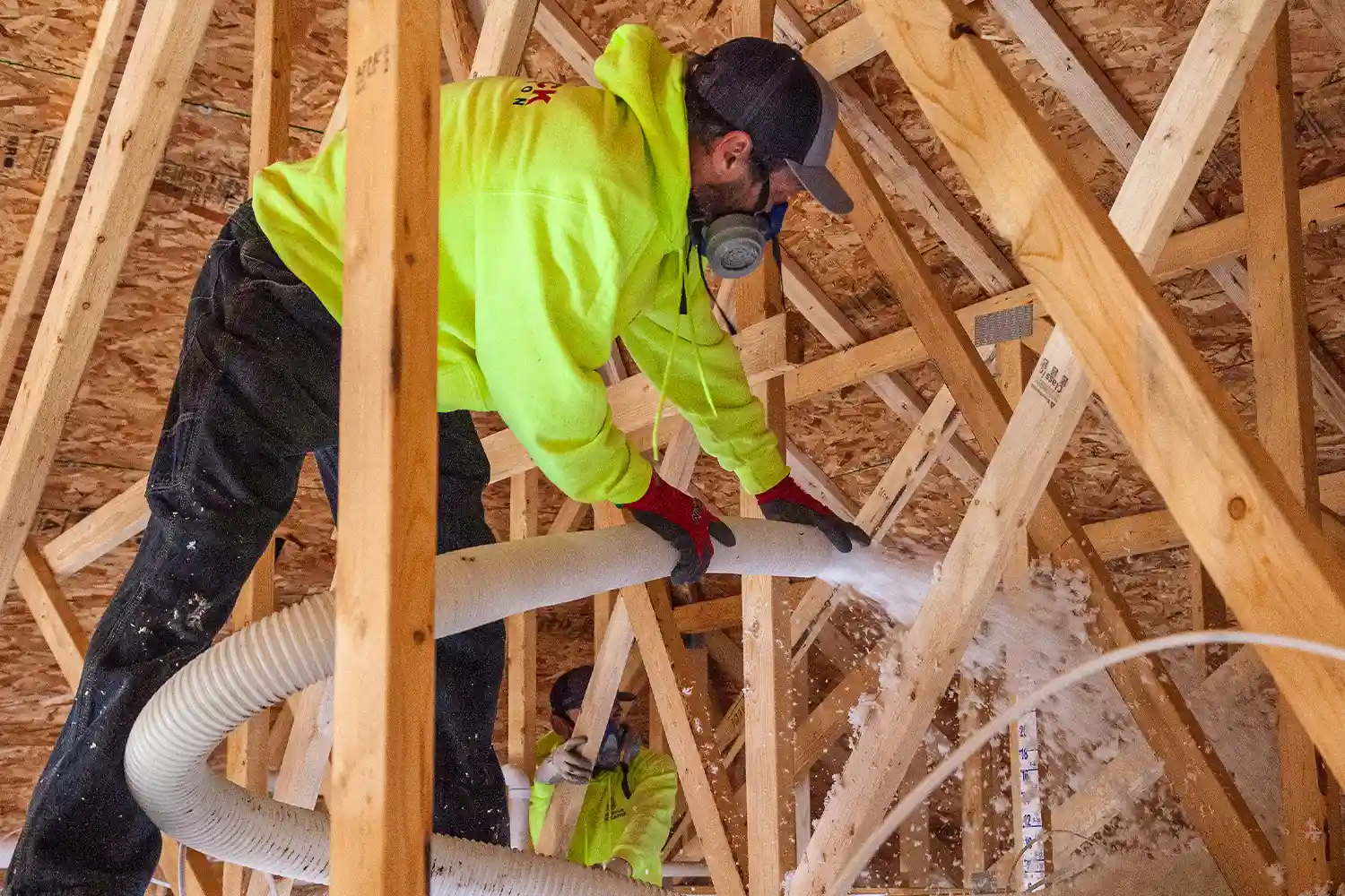 man using spray insulation in attic
